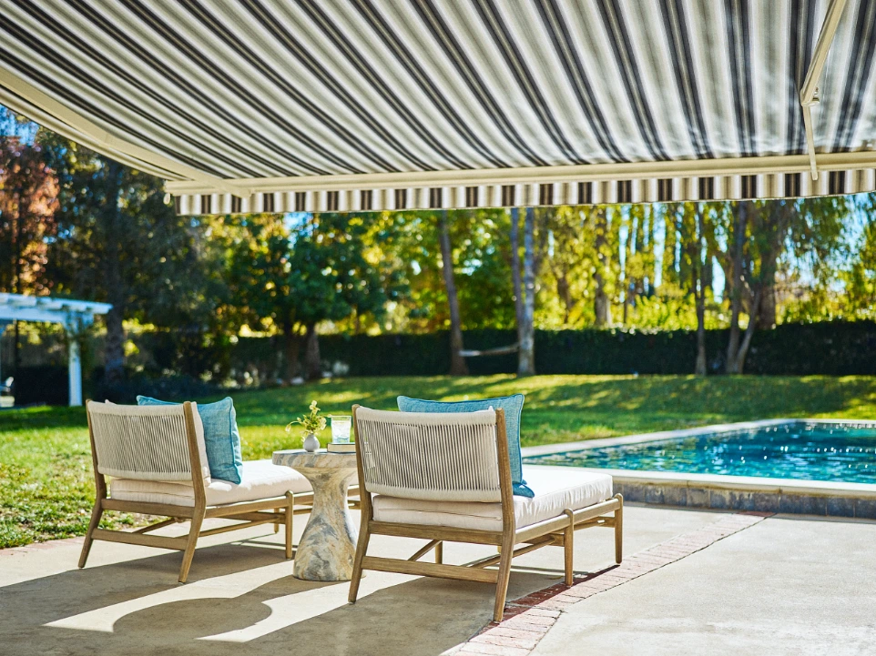 Striped retractable awning shading poolside lounge chairs